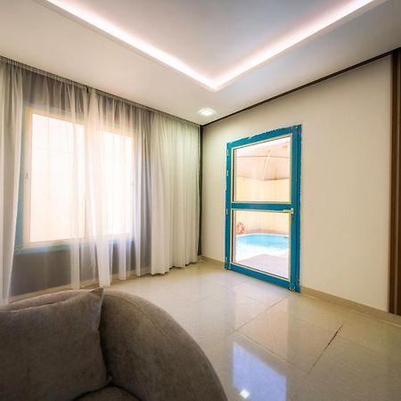 Mirada Gold Jizan - Resort & Private Pools Exterior photo The photo shows a modern interior space that appears to be a room in a home or a building. There is a large window with sheer curtains letting in natural light, which contributes to a bright and airy atmosphere. On one side of the room, there is a sl