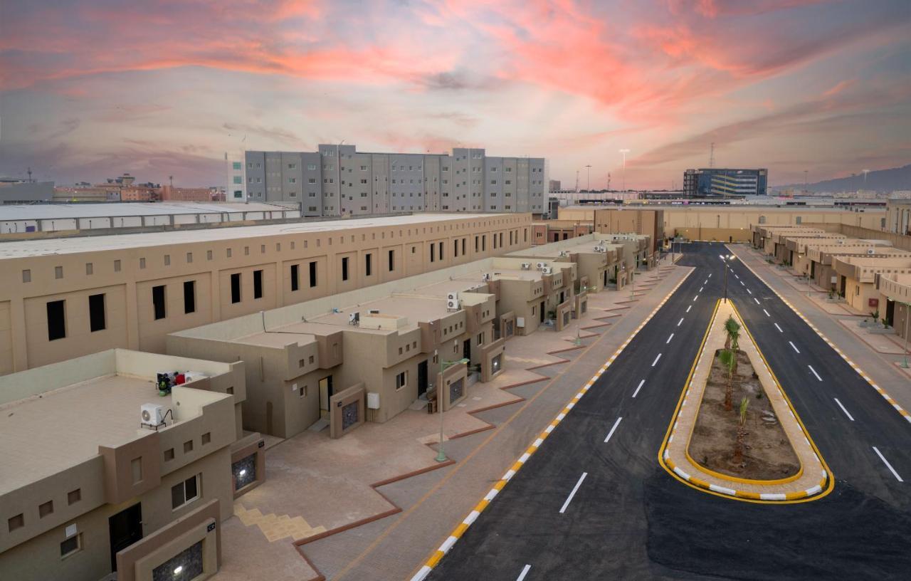 Mirada Gold Jizan - Resort & Private Pools Exterior photo The photo shows a modern residential area with a series of light-colored buildings lined along a road. The architecture appears to be contemporary, featuring low-rise structures that include individual homes or apartments. The street is well-maintain